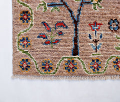 A handmade Afghan wool rug featuring a tan field with floral motifs and a decorative border.