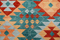 Handmade Afghan Pashm rug featuring a geometric pattern in teal, red, and orange wool.