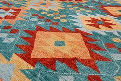 A handmade Afghan wool rug featuring a geometric pattern in shades of teal, orange, and red.