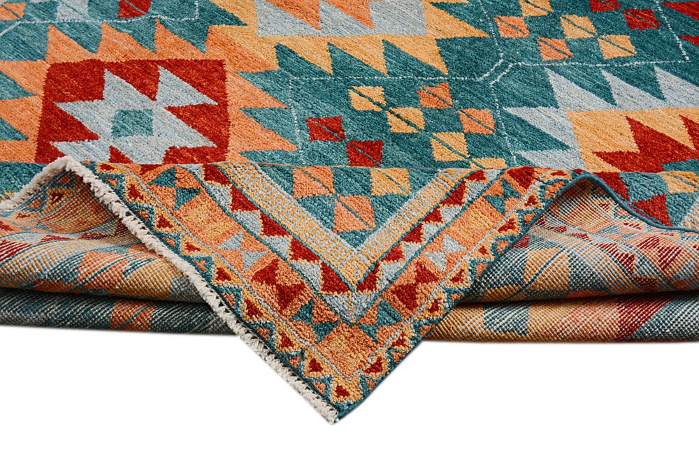 A handmade Afghan wool rug featuring a geometric pattern in teal, orange, and red.
