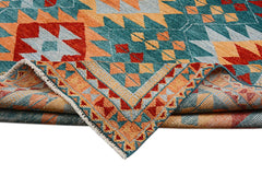 A handmade Afghan wool rug featuring a geometric pattern in teal, orange, and red.