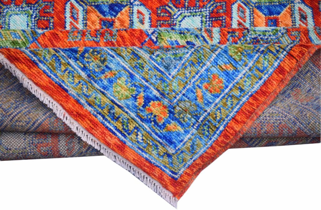 A handmade Afghan Pashm wool rug featuring a vibrant blue and orange geometric tribal pattern.