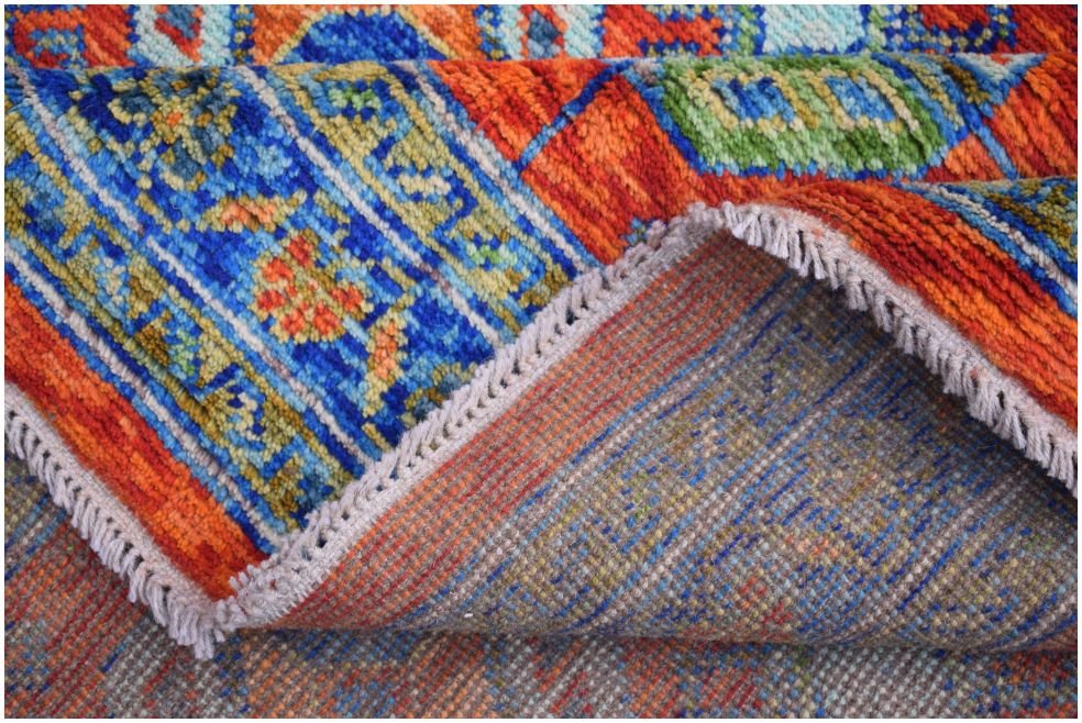 A handmade Afghan wool rug featuring a vibrant, colorful geometric tribal pattern.