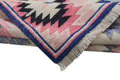 A folded Afghan Pashm wool rug featuring a geometric tribal pattern in pink, black, and blue.