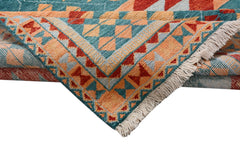 A handmade Afghan wool rug featuring a geometric tribal pattern in teal, orange, and red.