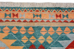 A handmade Afghan wool rug featuring a geometric tribal pattern in teal, orange, and red.