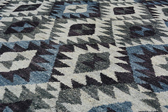 A handmade Afghan wool rug featuring a geometric diamond pattern in shades of blue, grey, and cream.