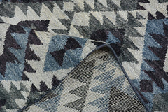 A handmade Afghan wool rug featuring a geometric kilim pattern in shades of blue, grey, and black.