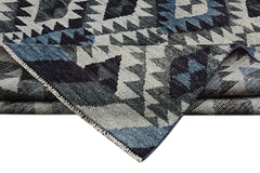 A handmade Afghan wool rug featuring a geometric pattern in shades of blue, grey, and black.