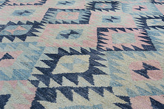 A handmade Afghan wool rug featuring a geometric pattern in shades of blue, pink, and cream.