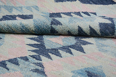 A handmade Afghan wool rug featuring a geometric pattern in shades of blue, pink, and cream.