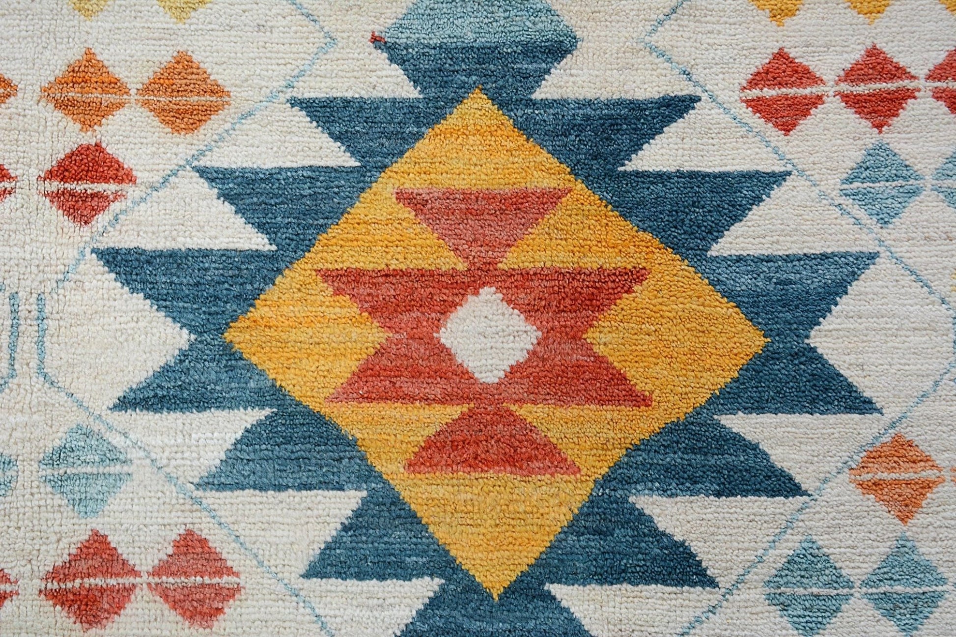 Handmade Afghan wool rug featuring a geometric tribal pattern in blue, yellow, and orange.
