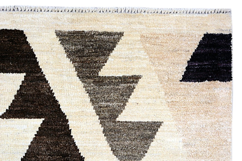 A handmade Afghan Pashm rug featuring a geometric pattern of dark brown and black triangles on a cream background.