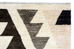A handmade Afghan Pashm rug featuring a geometric pattern of dark brown and black triangles on a cream background.