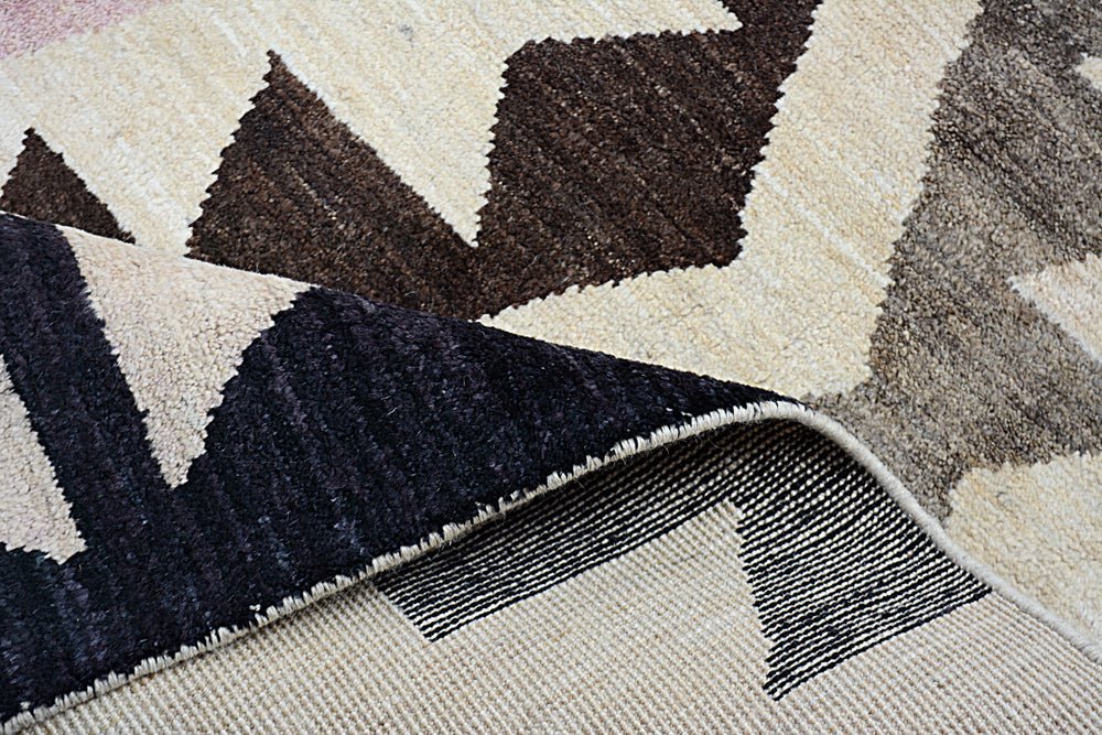 A handmade Afghan Pashm rug featuring a geometric pattern in cream and dark brown wool.