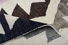 A handmade Afghan Pashm rug featuring a geometric pattern in cream and dark brown wool.