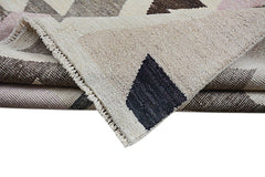 A handmade Afghan Pashm rug featuring a geometric pattern in cream, brown, and soft pink tones.