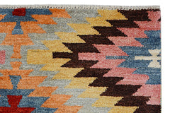 A handmade Afghan wool rug featuring a colorful geometric kilim pattern in a plush pile.