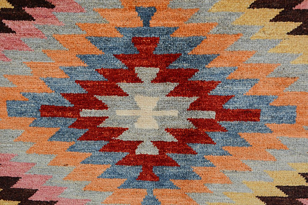 Handmade Afghan wool rug featuring a geometric kilim pattern in shades of red, blue, and orange.