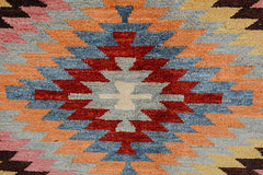 Handmade Afghan wool rug featuring a geometric kilim pattern in shades of red, blue, and orange.