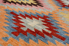 A handmade Afghan wool rug featuring a geometric kilim pattern in shades of blue, red, and orange.