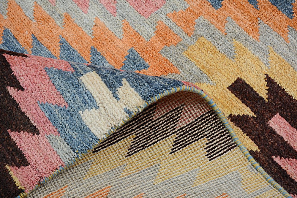 A handmade Afghan Pashm rug featuring a colorful geometric kilim pattern and a plush wool pile.