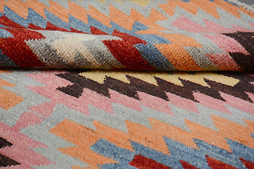 A handmade Afghan wool rug featuring a colorful geometric pattern in a plush, textured pile.
