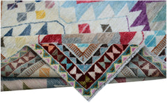 A handmade Afghan wool rug featuring a colorful geometric tribal pattern folded to show detail.