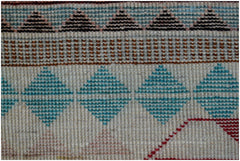 A close-up of a handmade Afghan wool rug featuring geometric patterns in blue, brown, and red.