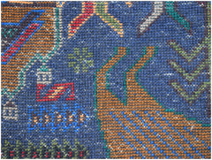 A close-up of a handmade Afghan wool runner featuring a detailed hunting scene on a blue background.