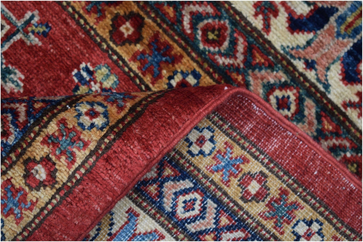 A handmade Afghan Super Kazakh rug featuring traditional geometric patterns in red, blue, and gold.