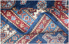 A folded Afghan Super Kazakh rug featuring traditional geometric patterns in blue, red, and cream.