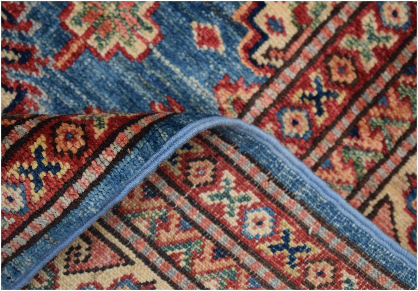 A handmade Afghan Super Kazakh rug featuring a blue field with traditional geometric patterns.