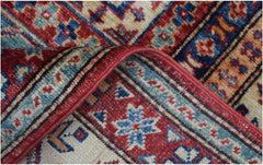 A close-up of a handmade Afghan Super Kazakh rug featuring intricate geometric patterns in red and blue.