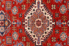 A handmade Afghan Super Kazakh rug featuring a central geometric medallion on a red background.