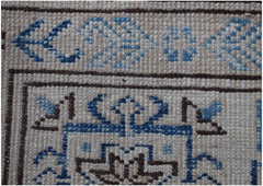 A close-up of an Afghan Super Kazakh rug featuring intricate blue and brown geometric patterns.