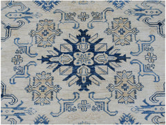 Handmade Afghan Super Kazakh rug featuring a central blue geometric medallion on a cream field.