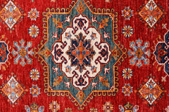 A handmade Afghan Super Kazakh rug featuring a central medallion on a vibrant red field.