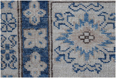 A close-up of an Afghan Super Kazakh rug featuring blue and cream geometric floral patterns.