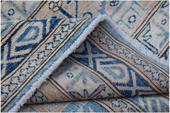 A folded Afghan Super Kazakh rug featuring traditional blue and beige geometric patterns.