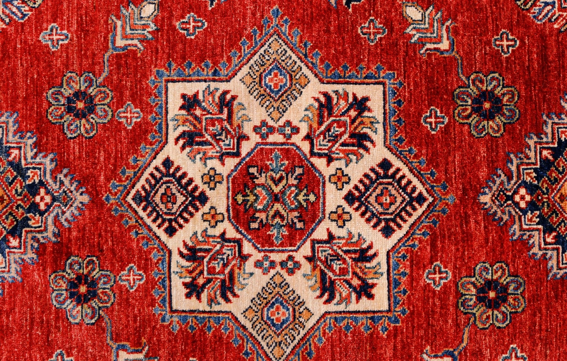 A handmade Afghan Super Kazakh rug featuring a central geometric star motif on a red background.