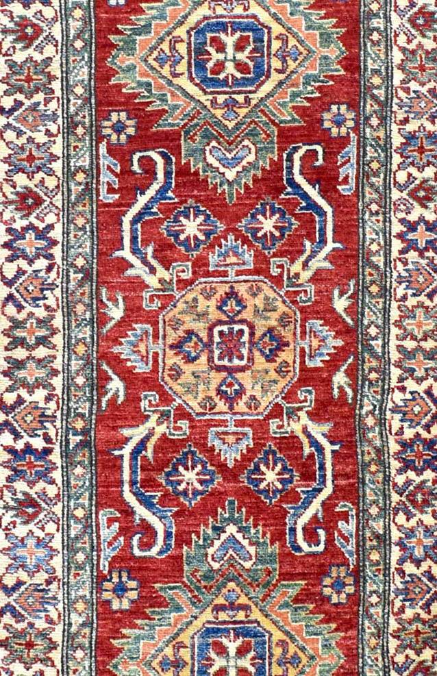 Handmade Afghan Super Kazakh runner rug featuring a geometric red field with blue and cream motifs.