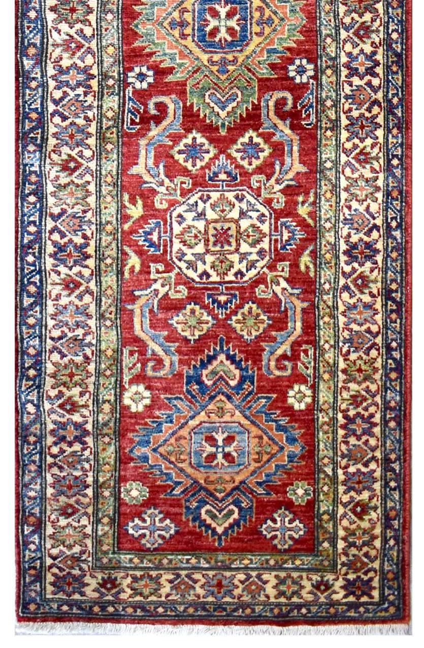 Handmade Afghan Super Kazakh runner rug featuring geometric patterns in red, blue, and cream.