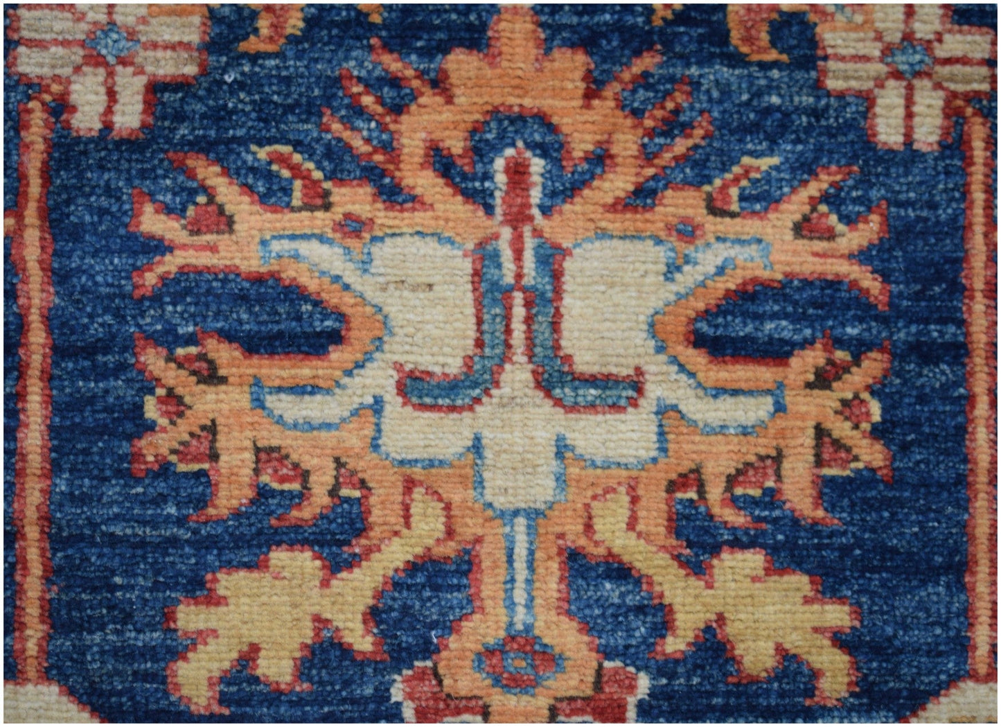 A close-up of an Afghan Super Kazakh runner featuring a stylized floral motif in orange and cream.