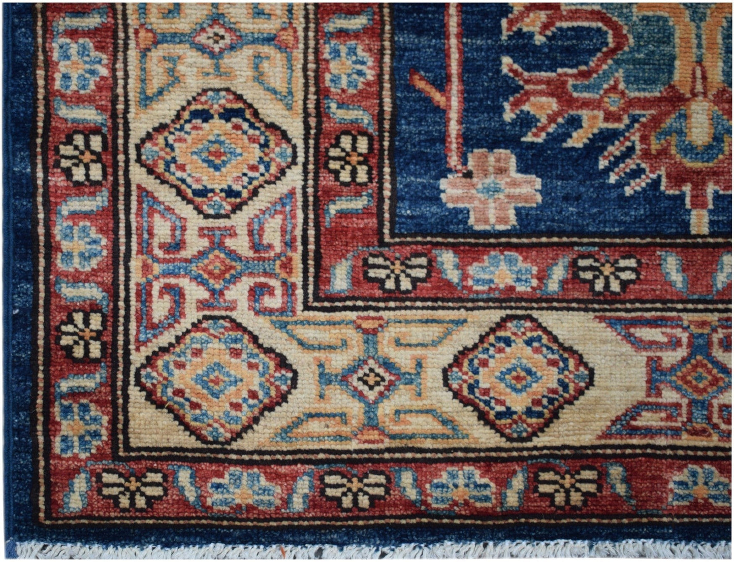 A handmade Afghan Super Kazakh runner featuring a geometric pattern in blue, red, and cream.