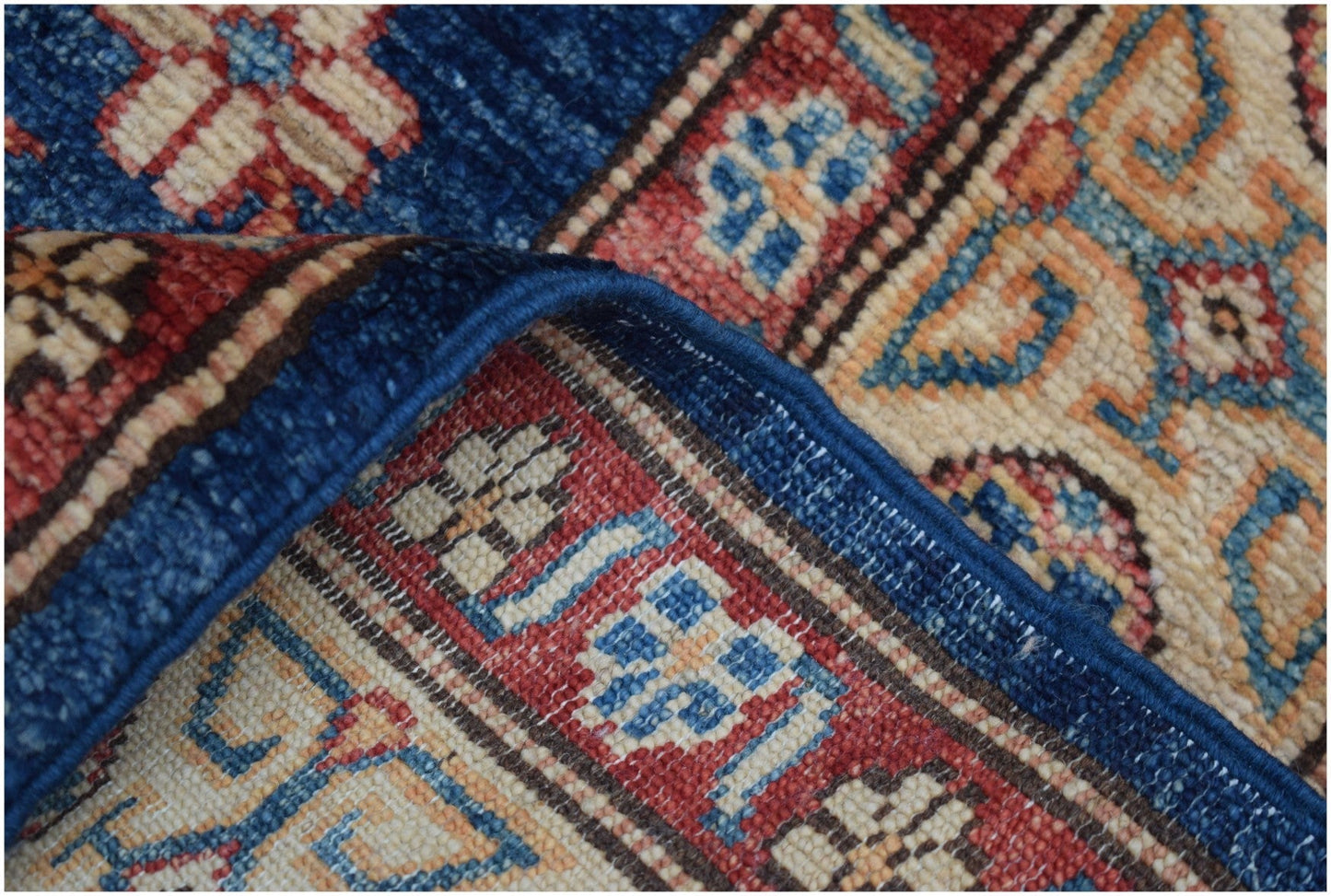 A corner of a handmade Afghan Super Kazakh runner rug showing intricate geometric patterns.