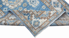 A folded Afghan Super Kazakh runner featuring traditional blue and beige geometric patterns.