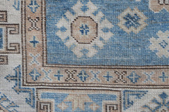 A close-up of an Afghan Super Kazakh runner featuring traditional blue and beige geometric motifs.