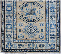 Handmade Afghan Super Kazakh runner rug featuring blue geometric patterns on a beige wool field.