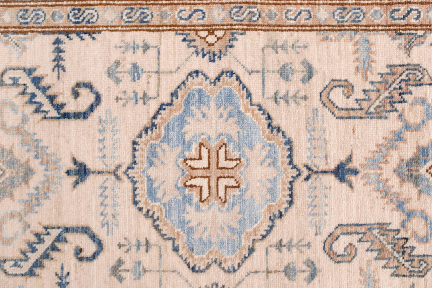 A hand-knotted Afghan Super Kazakh runner featuring a central blue medallion on a cream field.